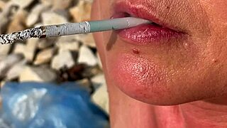 Blonde milf smokes cigarettes on the beach from day to sunset