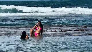 Two pretty brunettes kiss on the public beach at enseada dos corais