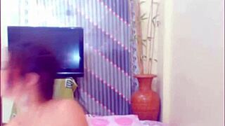 The performer demonstrates a self-sucking technique in an amateur setting